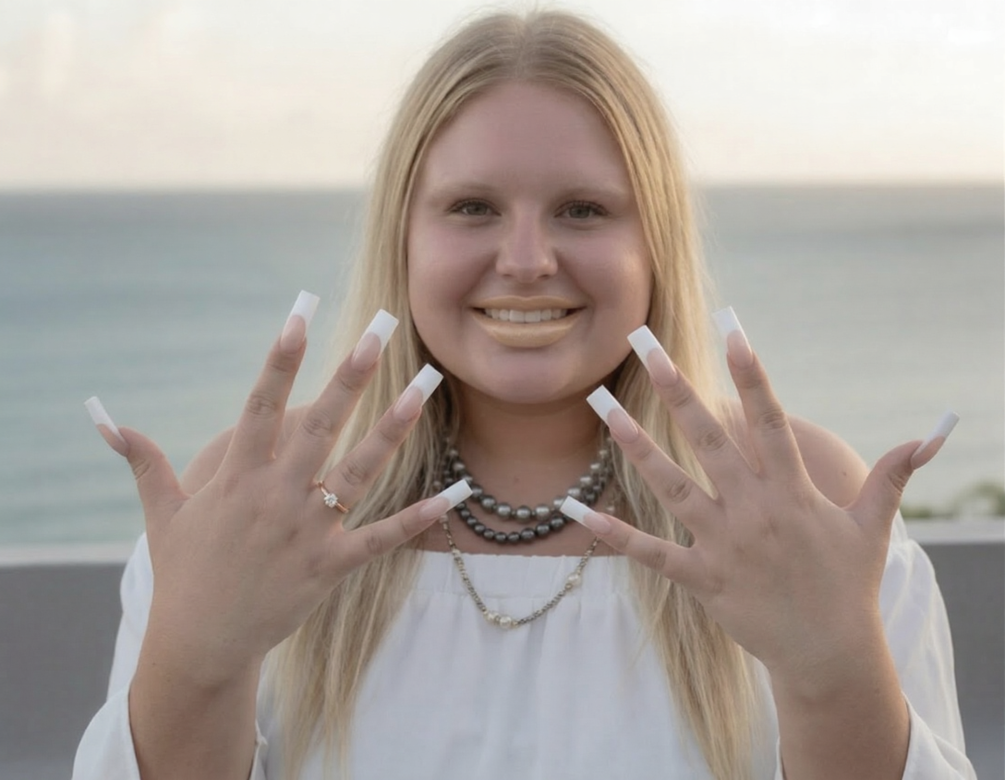 Source photo — blonde woman showing nails, ocean background, white dress